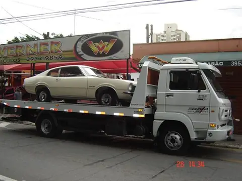 Guincho entregando carro clássico em loja de veículos