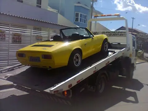 Carro conversível amarelo sobre guincho plataforma