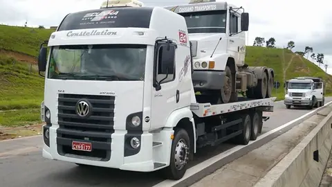 Guincho plataforma transportando caminhão na rodovia